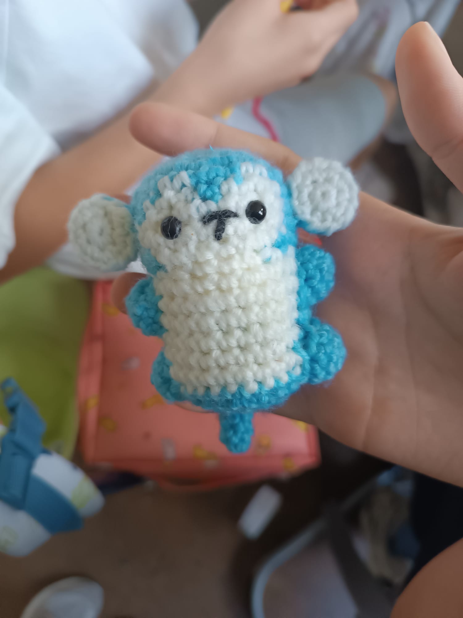 Selbstgehäkelte kleine Figur in Blau und Weiß, in einer Hand gehalten